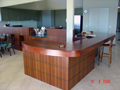 Curved solid Jarrah benchtop with display niches in servery panel in background